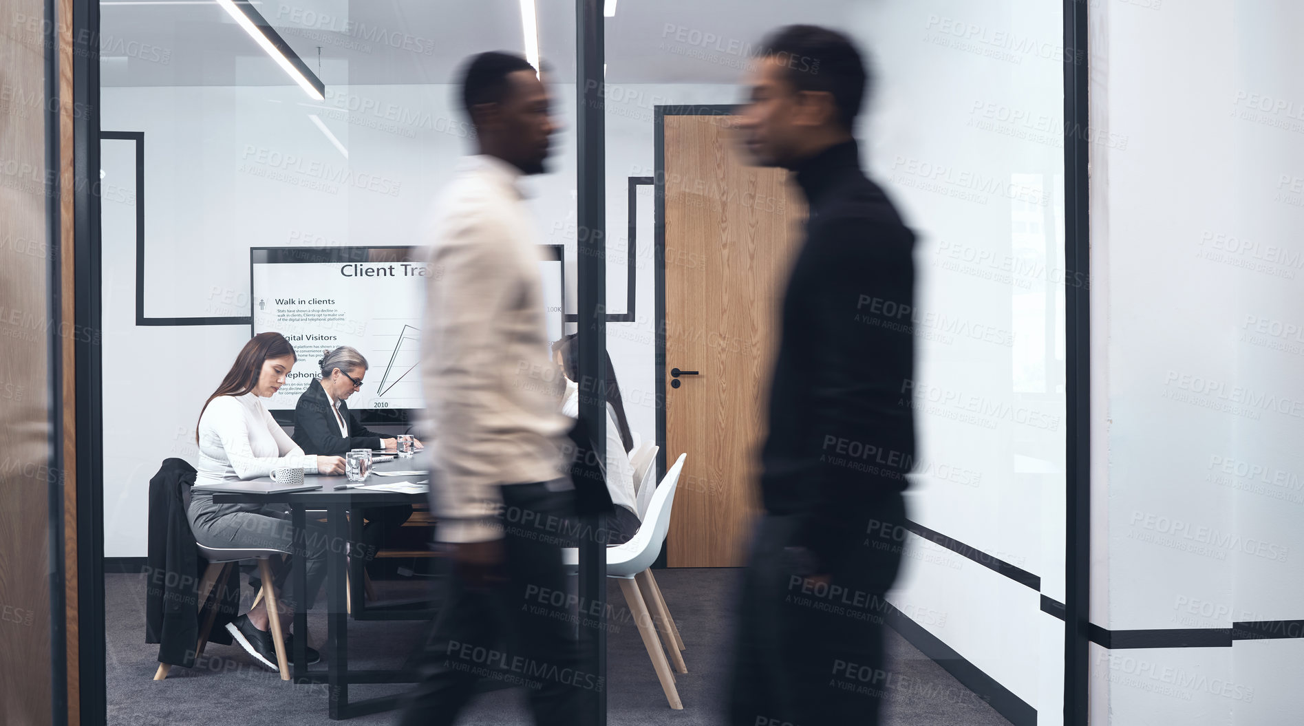 Buy stock photo Shot of two work colleagues walking by one another at the office
