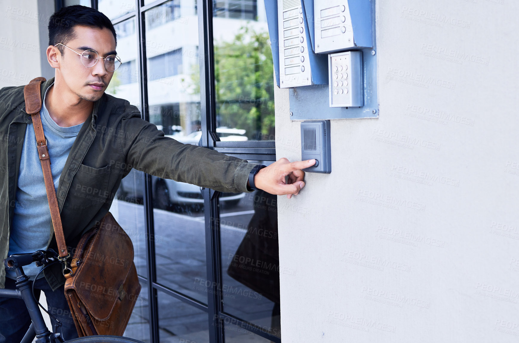 Buy stock photo Shot of a young man pressing a button outside of a building