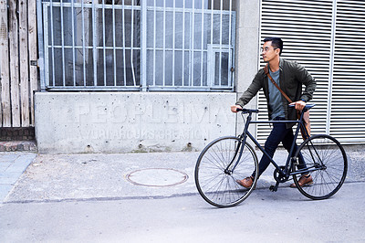 Buy stock photo Shot of a young man using a bicycle in the city
