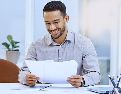 Buy stock photo Shot of a businessman looking at paperwork while sitting at his desk