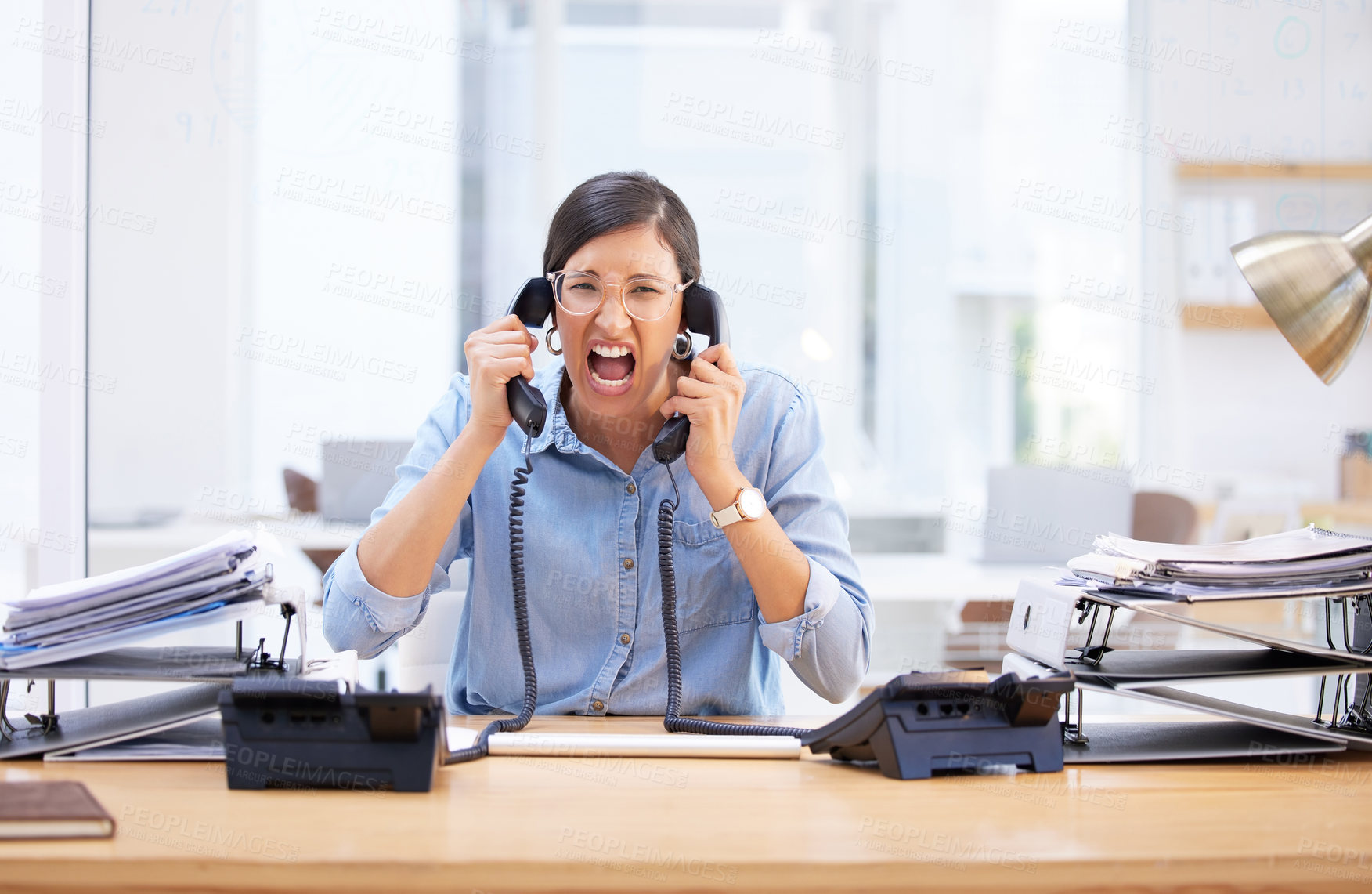 Buy stock photo Shot of a young businesswoman screaming in frustration at her telephone