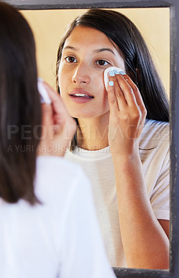 Buy stock photo Shot of a beautiful young woman looking in the mirror while cleaning her face