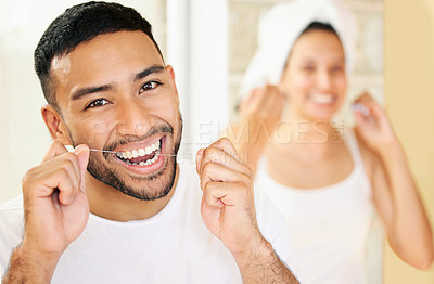 Buy stock photo Shot of a happy young couple flossing their teeth in the bathroom at home