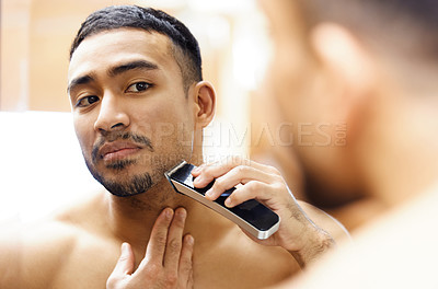 Buy stock photo Shot of a young man using an electric shaver