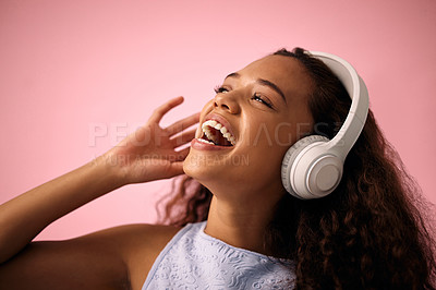 Buy stock photo Studio shot of a beautiful young woman wearing headphones while standing against a pink background