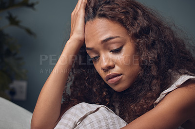 Buy stock photo Shot of a young woman looking unhappy while sitting at home