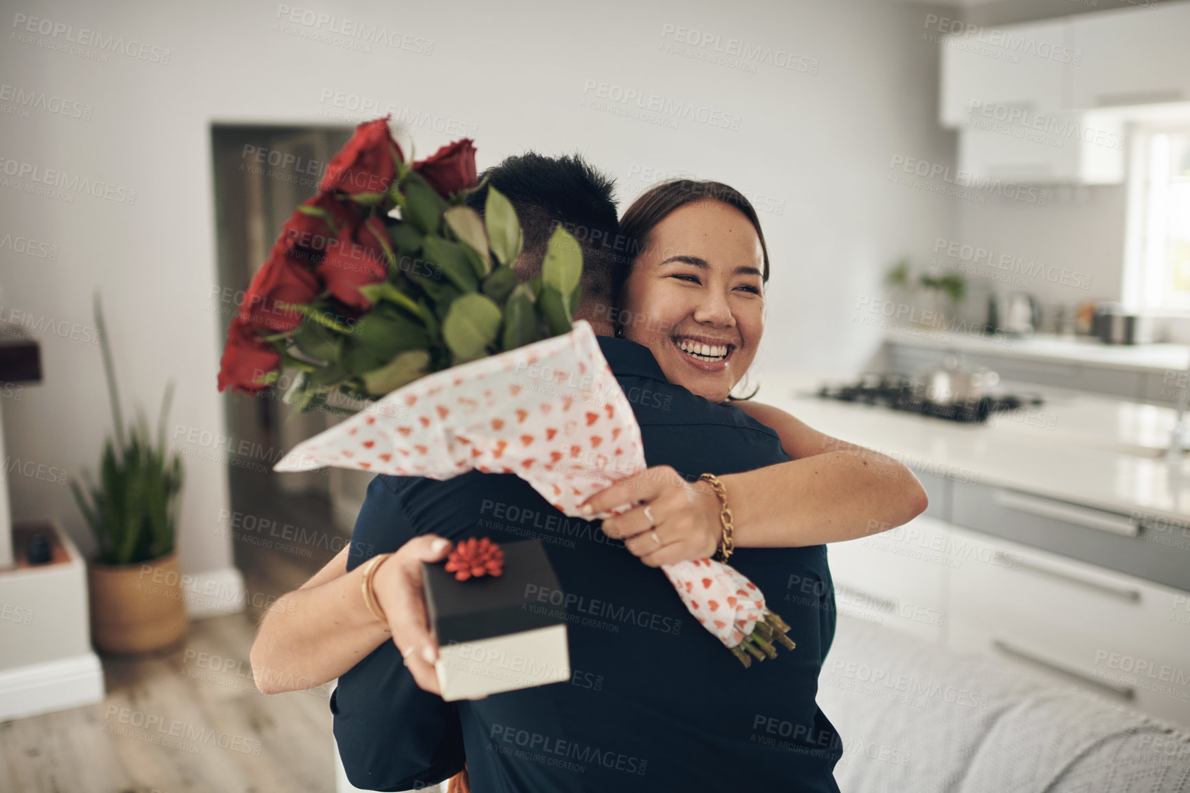 Buy stock photo Couple hug, home and roses present surprise of an Asian woman on valentines day. Living room, rose bouquet and lounge of people with love, care and happiness together with a smile from present