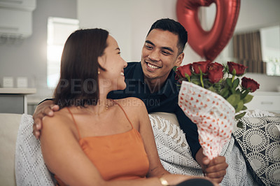 Buy stock photo Valentines day, flowers and couple on a living room sofa with a present and a smile. Happy, love and care of young people together with celebration rose on a date in a house on a couch with a gift