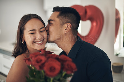 Buy stock photo Love, rose and valentines day with a couple kissing in their home, in celebration of romance. Dating, flower boquet or surprise with a man and woman in a house to kiss while bonding in intimacy