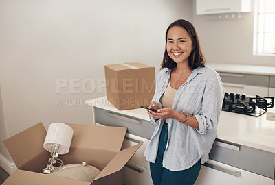 Buy stock photo Shot of a woman using her cellphone while standing in room with unpacked boxes