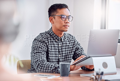 Buy stock photo Shot of a young businessman using a laptop in an office