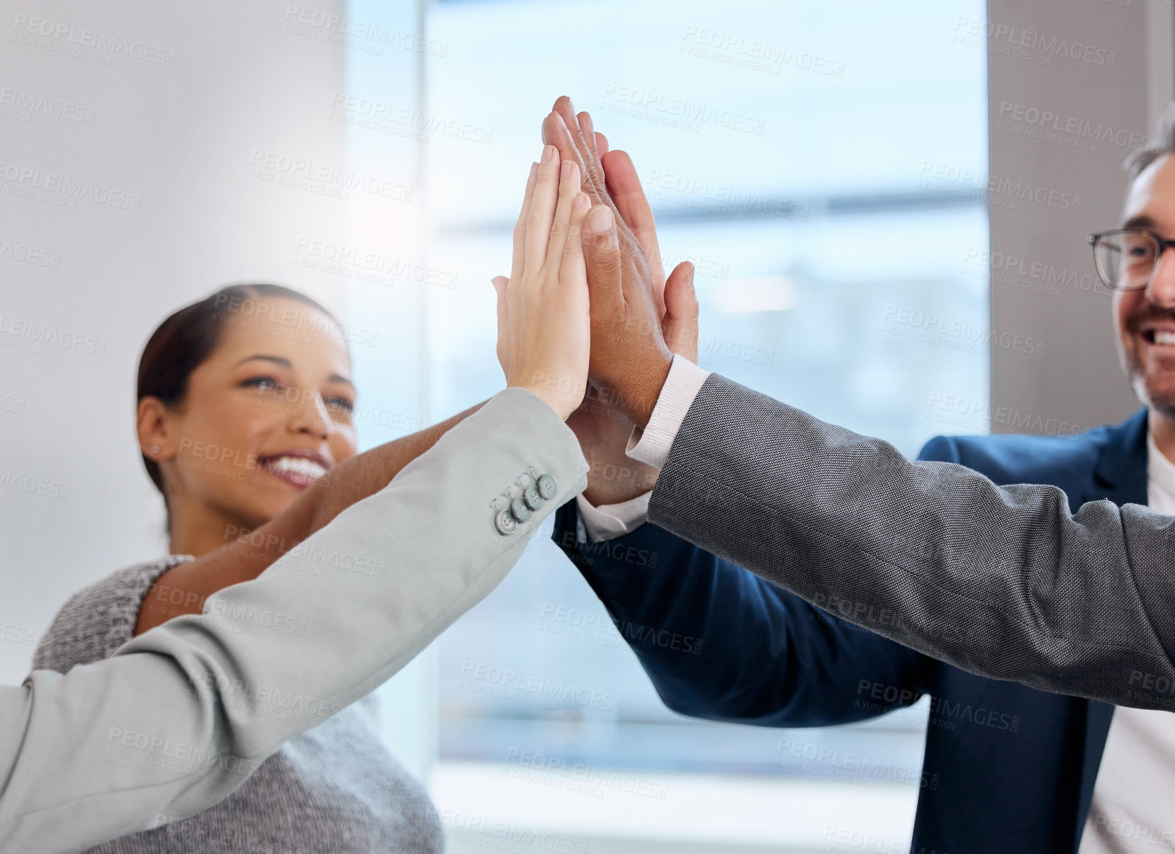 Buy stock photo Shot of a group of young businesspeople giving each other a high five at the office