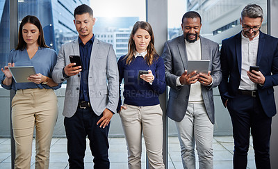 Buy stock photo Shot of a group of businesspeople using digital devices in an office
