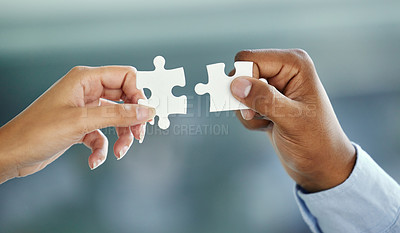 Buy stock photo Cropped shot of two unrecognizable businesspeople fitting puzzle pieces together while standing in their office