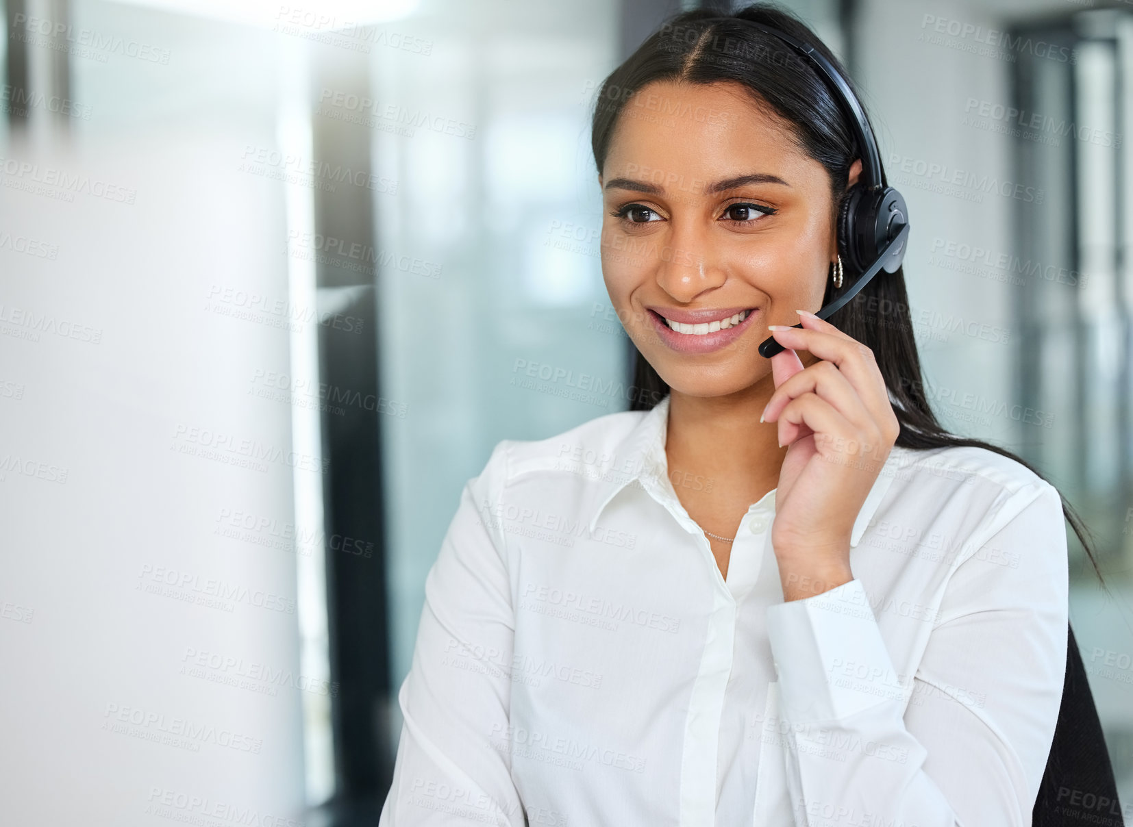 Buy stock photo Shot of an attractive young call centre agent sitting in the office and wearing a headset while using her computer