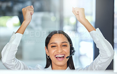 Buy stock photo Shot of a young call centre agent sitting in the office and wearing a headset while celebrating an achievement