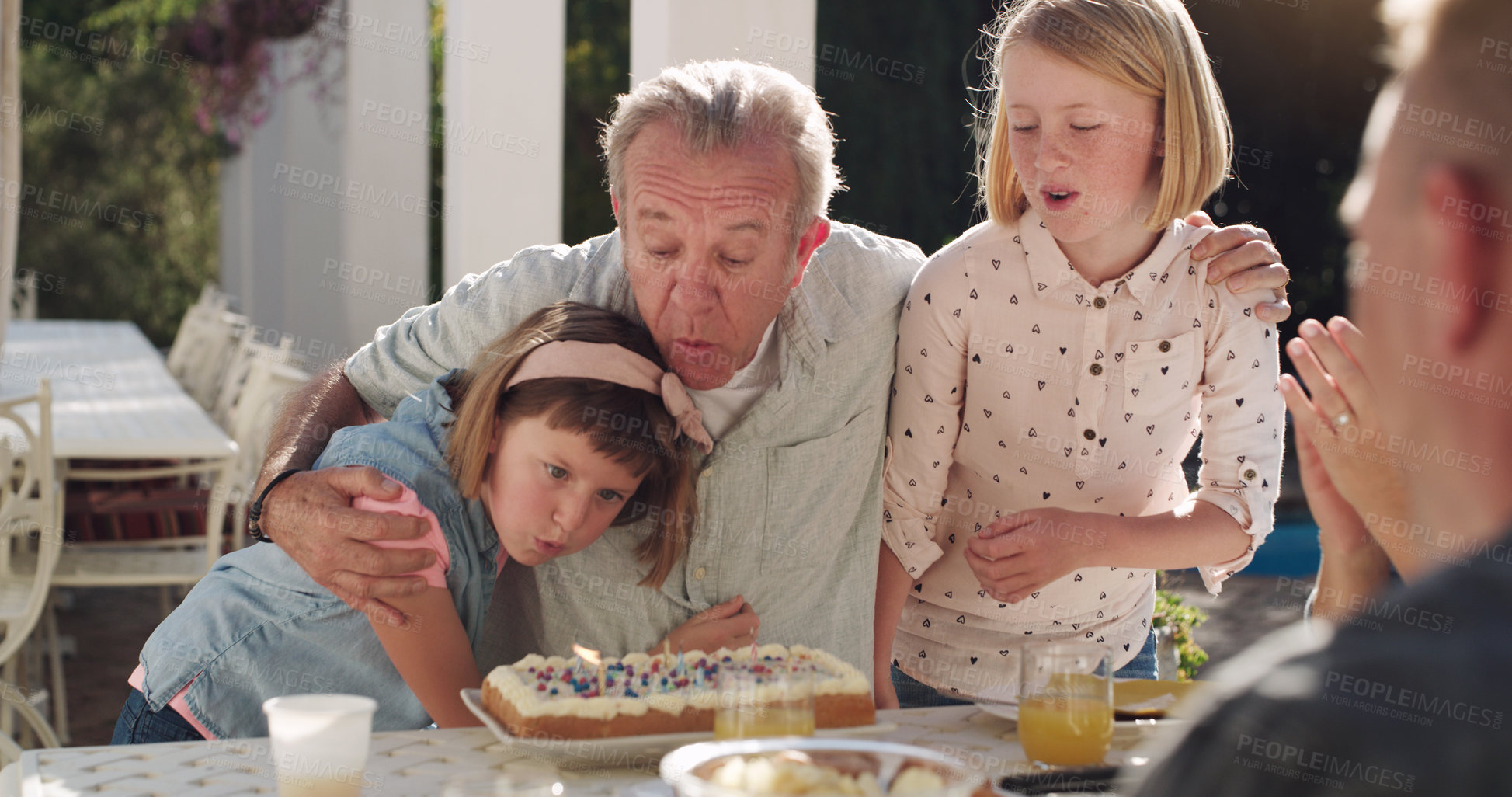 Buy stock photo Girl, grandfather and children with birthday cake in backyard for celebration, blow candle or party. Event, dessert and grandparent with kids for congratulation, milestone or make wish at home