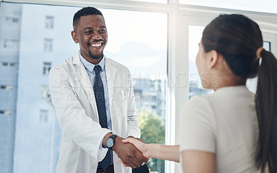 Buy stock photo Shot of a young male doctor shaking hands with a patient in an office