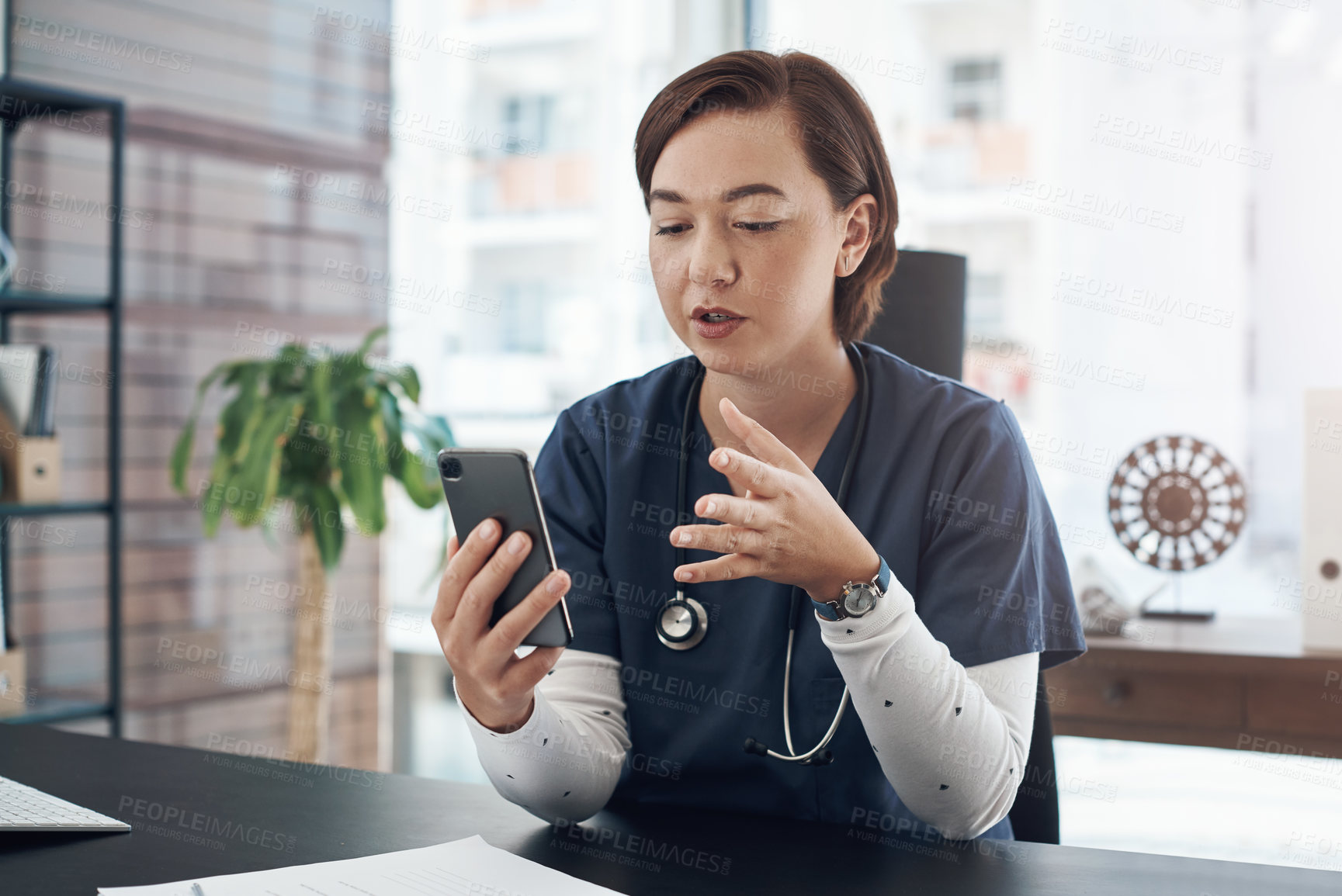 Buy stock photo Shot of a young doctor using a cellphone in an office