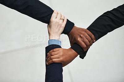 Buy stock photo High angle shot of a group of unrecognisable businesspeople holding onto each other’s arms in a modern office