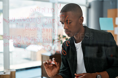 Buy stock photo Shot of a young businessman making notes in a modern office