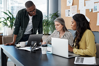 Buy stock photo Shot of a group of businesspeople brainstorming and using a laptop in a modern office