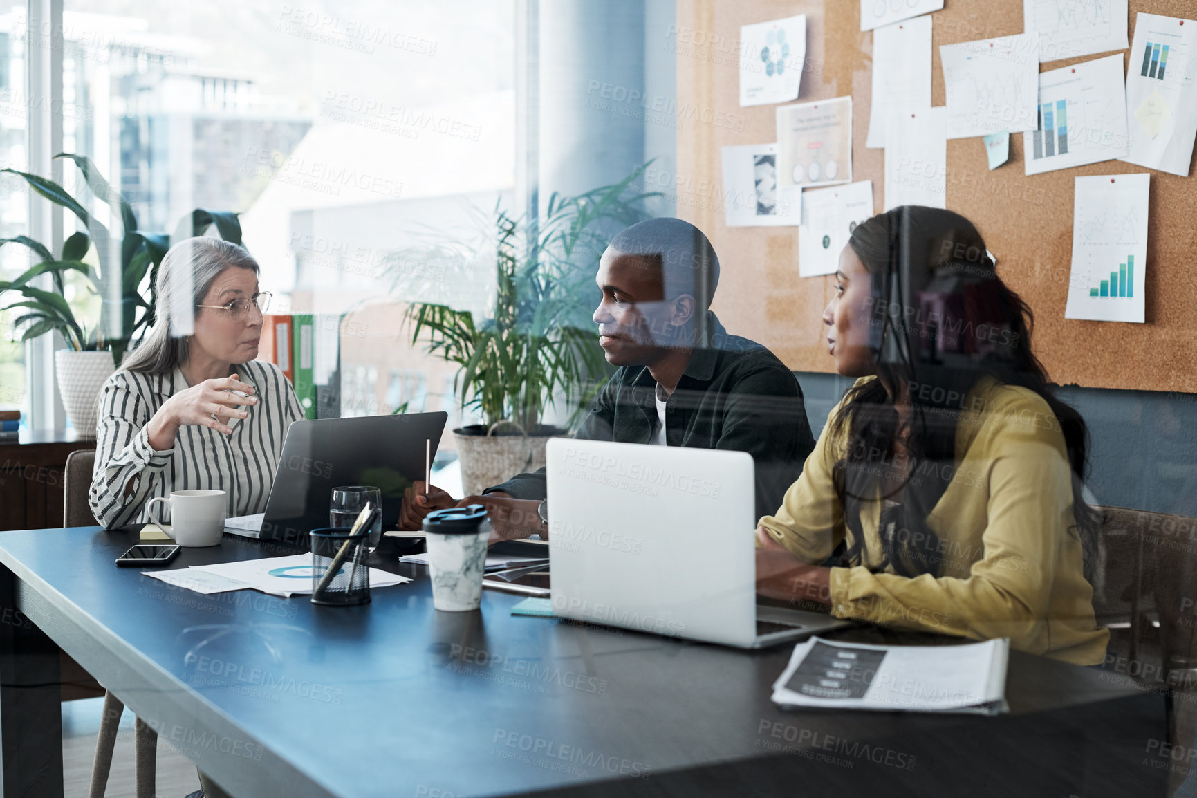 Buy stock photo Shot of a group of businesspeople brainstorming and using a laptop in a modern office