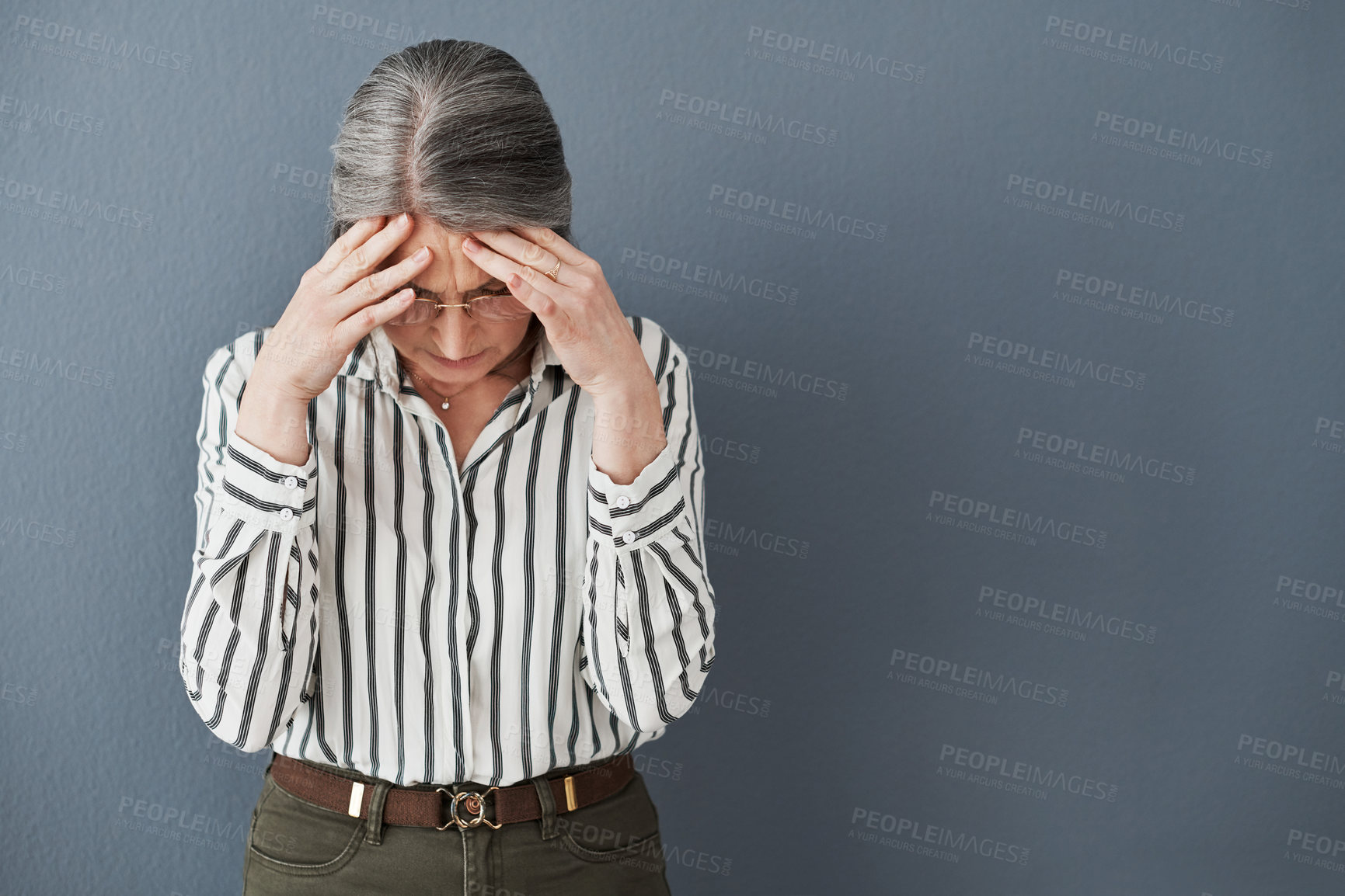 Buy stock photo Shot of a mature businesswoman holding her head suffering an intense headache against a black background