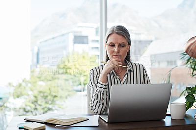 Buy stock photo Shot of a mature businesswoman using her laptop in a modern office