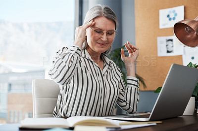 Buy stock photo Shot of a mature businesswoman suffering a major headache while using her laptop in a modern office