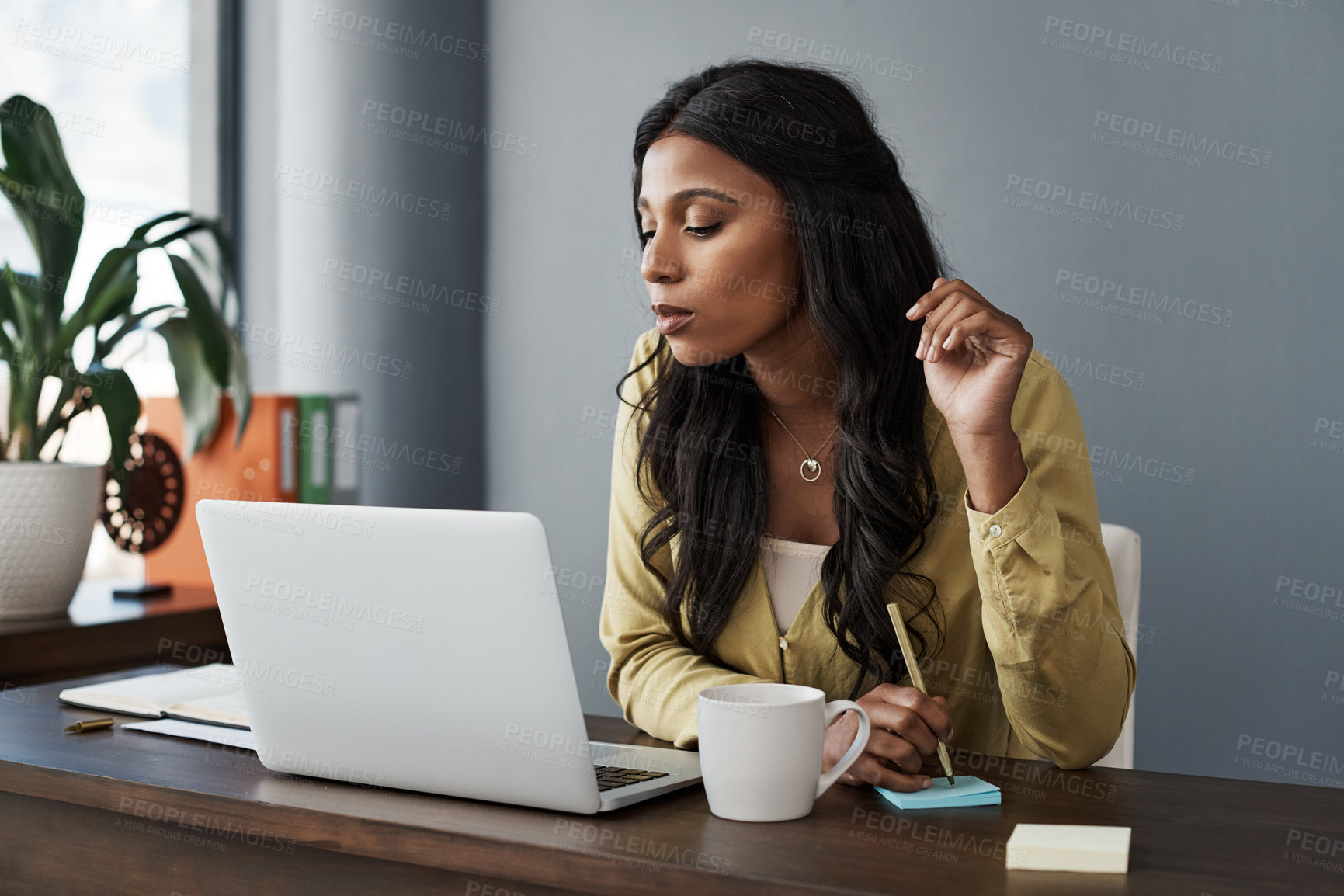 Buy stock photo Shot of a young businesswoman taking notes on a notepad