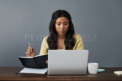 Buy stock photo Shot of a businesswoman taking notes while working from home