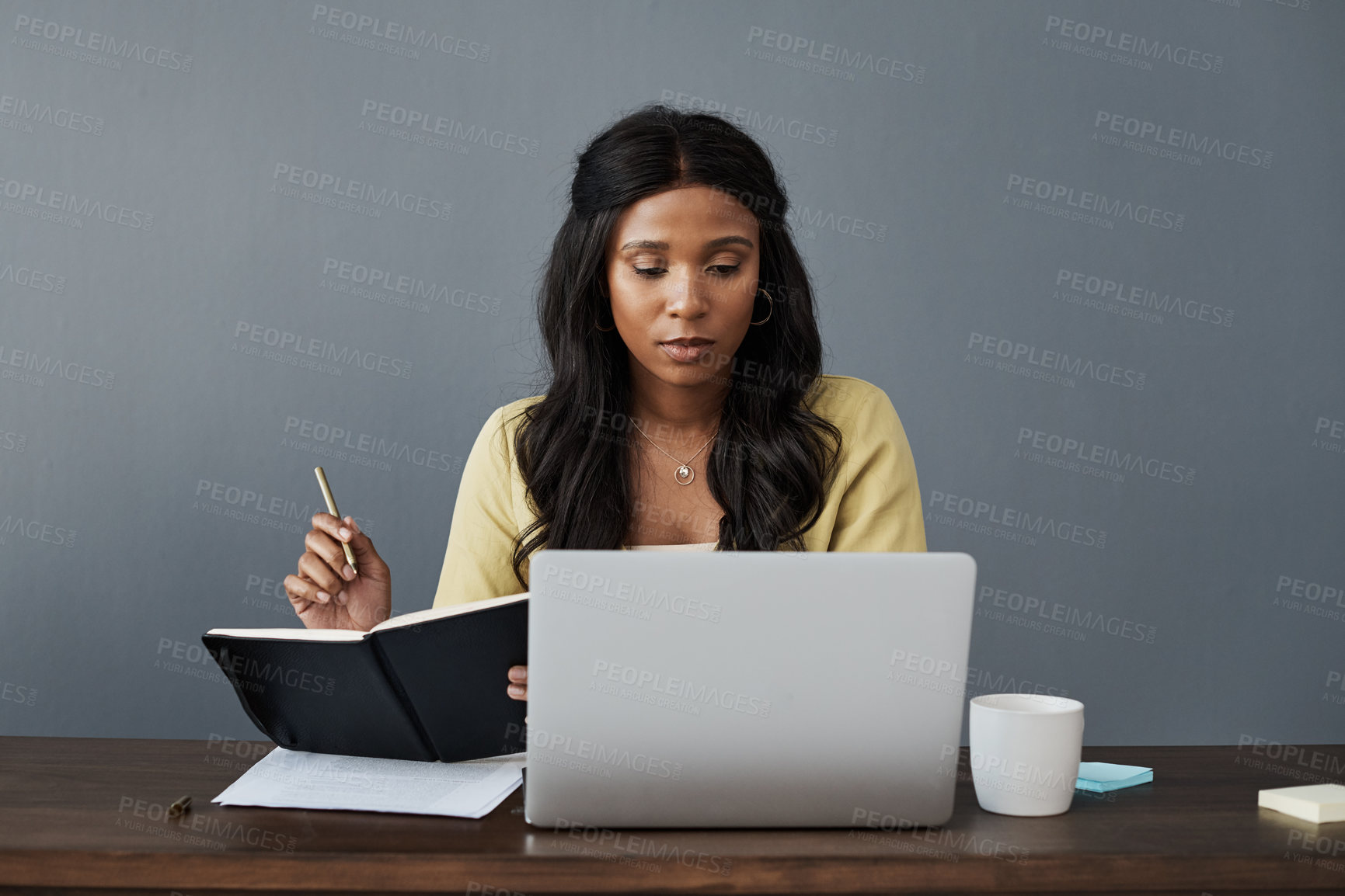 Buy stock photo Shot of a businesswoman taking notes while working from home