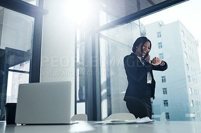 Buy stock photo Shot of a young businesswoman using a smartphone and checking the time in a modern office
