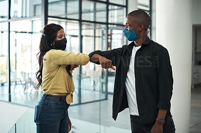 Buy stock photo Shot of two young people safely greeting one another during a pandemic in a modern office