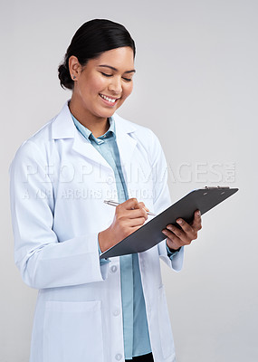 Buy stock photo Cropped shot of an attractive young female scientist working on a clipboard in studio against a grey background