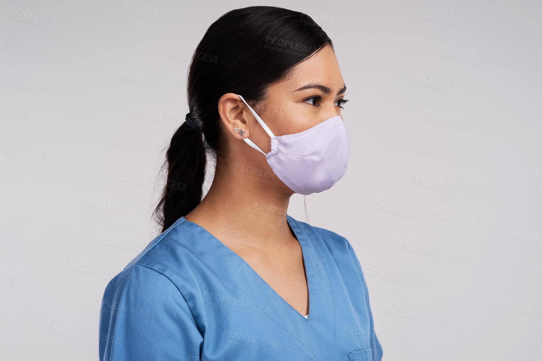 Buy stock photo Side shot of a young doctor wearing a surgical face mask against a white background