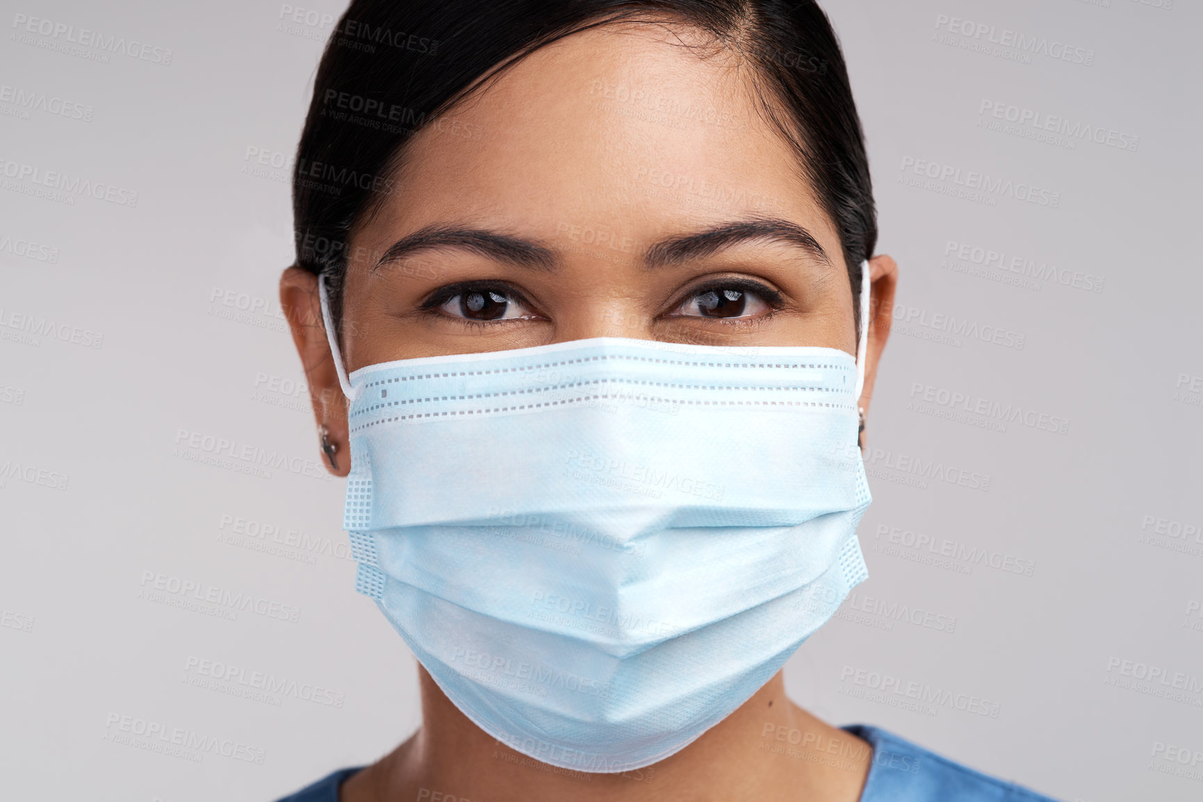 Buy stock photo Portrait of a young doctor wearing a surgical face mask against a white background