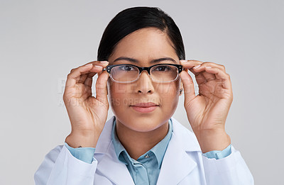 Buy stock photo Cropped portrait of an attractive young female scientist wearing glasses in studio against a grey background