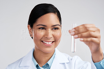 Buy stock photo Cropped shot of an attractive young female scientist examining a vial filled with liquid in studio against a grey background