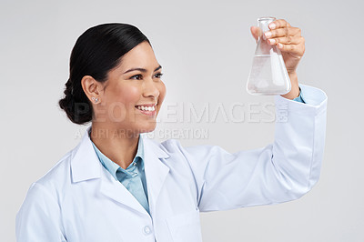 Buy stock photo Cropped shot of an attractive young female scientist examining a beaker filled with liquid in studio against a grey background