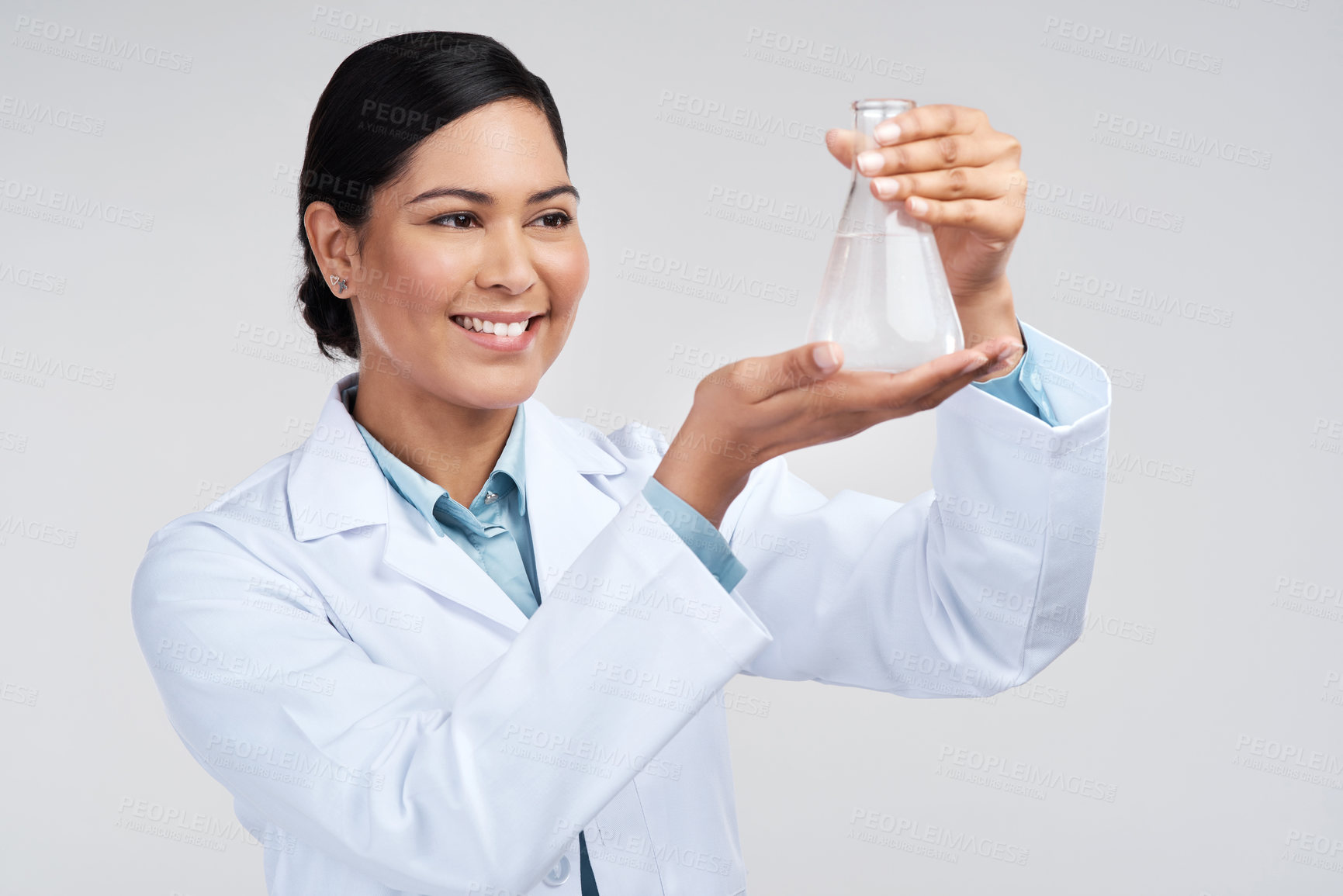 Buy stock photo Cropped shot of an attractive young female scientist examining a beaker filled with liquid in studio against a grey background