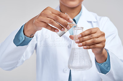Buy stock photo Cropped shot of an unrecognizable female scientist mixing samples in studio against a grey background
