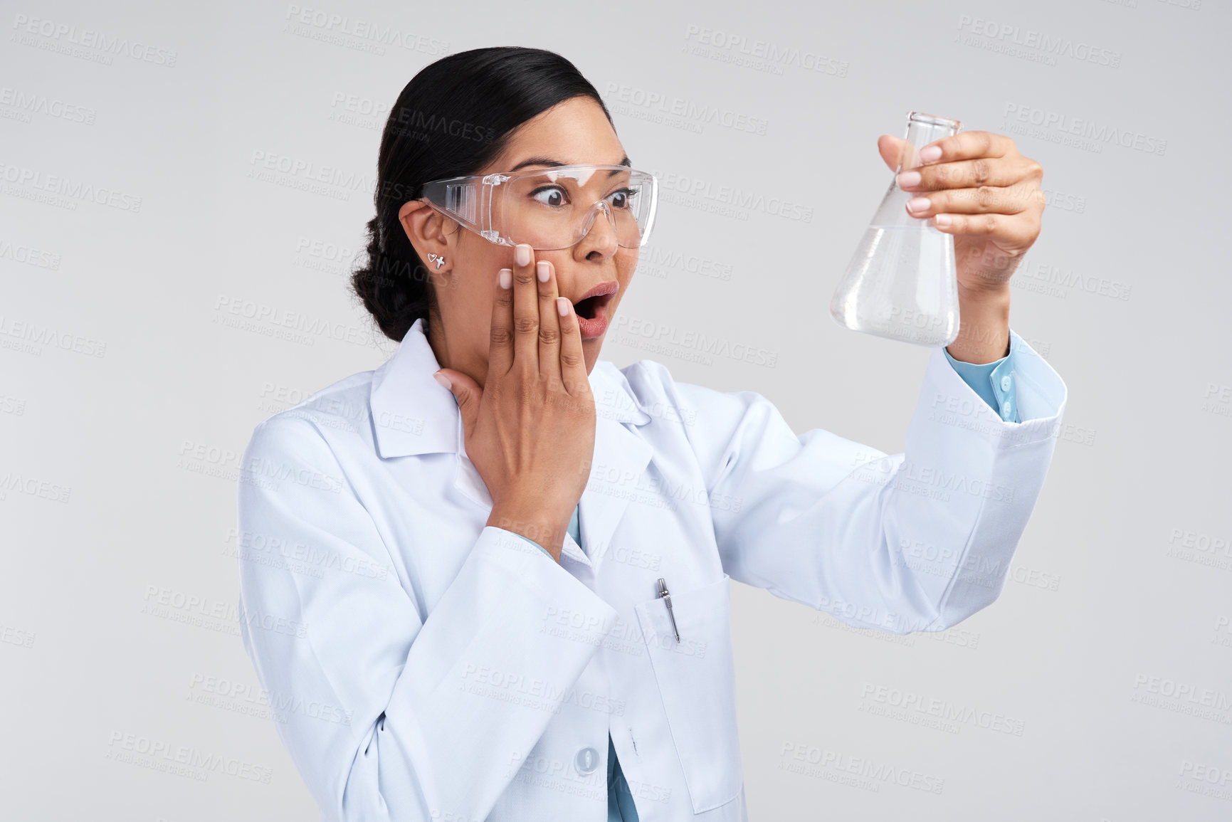 Buy stock photo Cropped shot of an attractive young female scientist looking shocked while examining a beaker filled with liquid in studio against a grey background