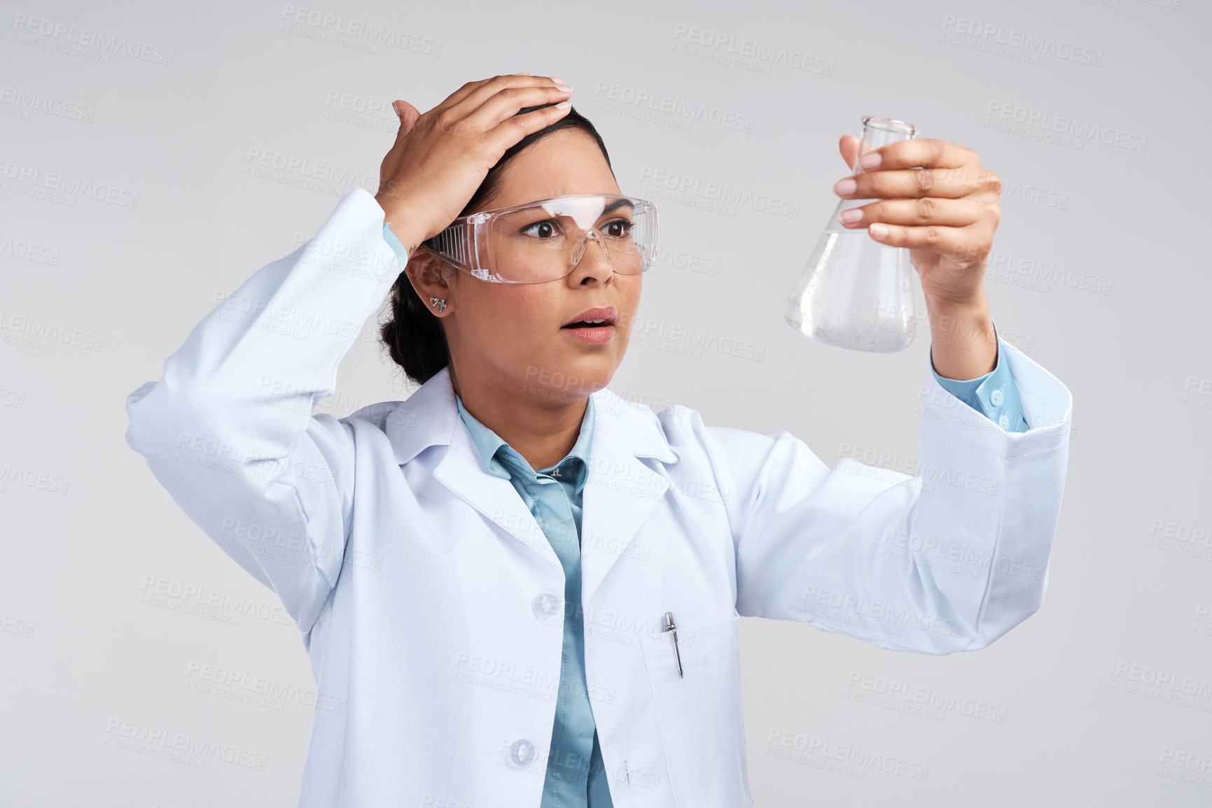 Buy stock photo Cropped shot of an attractive young female scientist looking shocked while examining a beaker filled with liquid in studio against a grey background