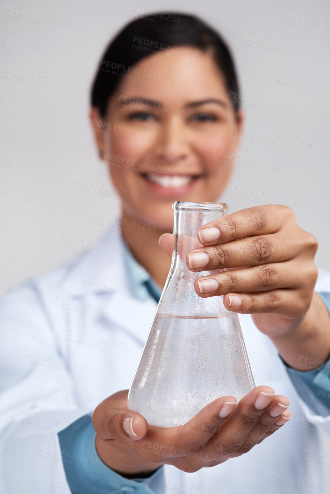 Buy stock photo Cropped portrait of an attractive young female scientist holding a beaker filled with liquid in studio against a grey background