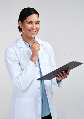 Buy stock photo Cropped portrait of an attractive young female scientist looking thoughtful while working on a clipboard in studio against a grey background