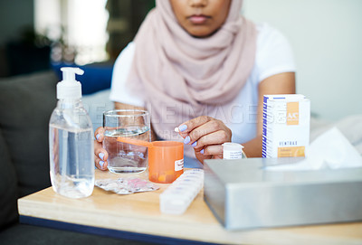 Buy stock photo Muslim, woman and sick with pills on sofa in living room with illness, flu and tired at home. Female person, lounge and fever with medication to relax, chill and calm on couch for recovery or rest
