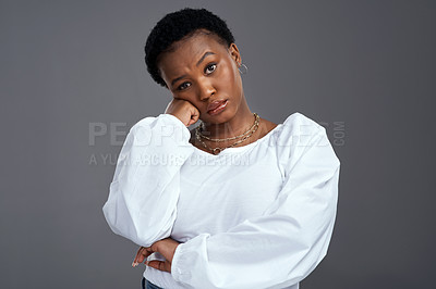 Buy stock photo Shot of a young woman looking serious while posing against a grey background