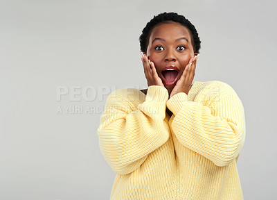 Buy stock photo Shot of a young woman looking surprised while posing against a grey background